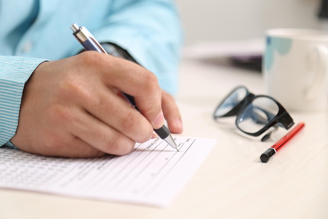 person-signing-papers-with-glasses-on-table