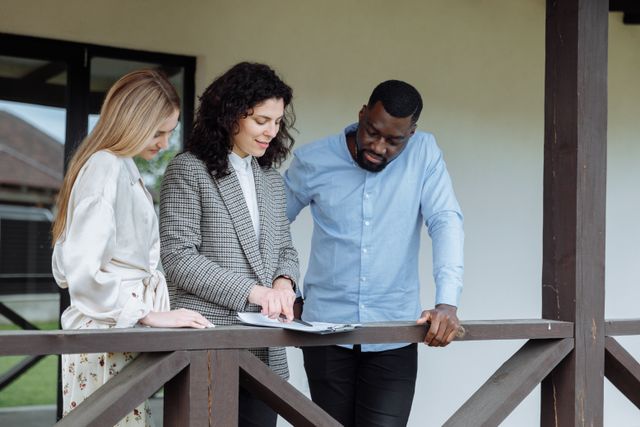 person discussing paperwork with two other people on a porch