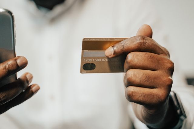 person holding a phone and a credit card